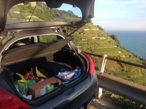 Image of a car trunk filled with suitcase, camping gear with food and chocolate filling in the gaps.